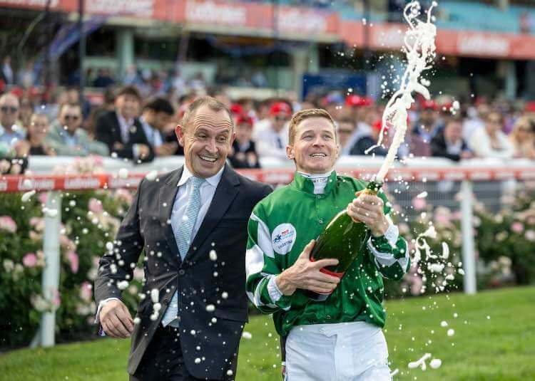 Chris Waller and James McDonald celebrate with a bottle of champagne after Via Sistina (Ire) wins the G1 W.S Cox Plate at Moonee Valley